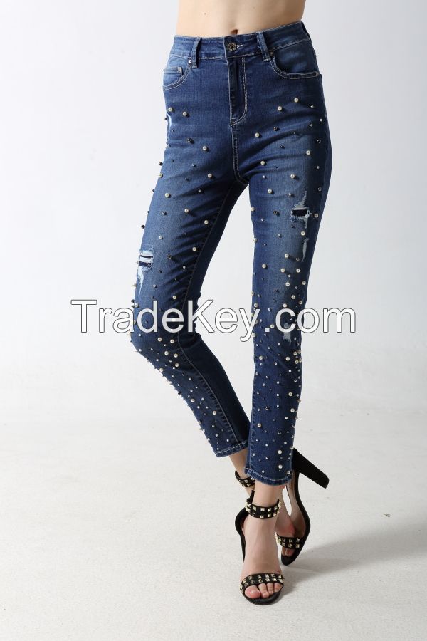 Woman's slim denim jeans with rips and full studs at front