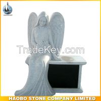 Grey granite angel sitting on yellow marble bench