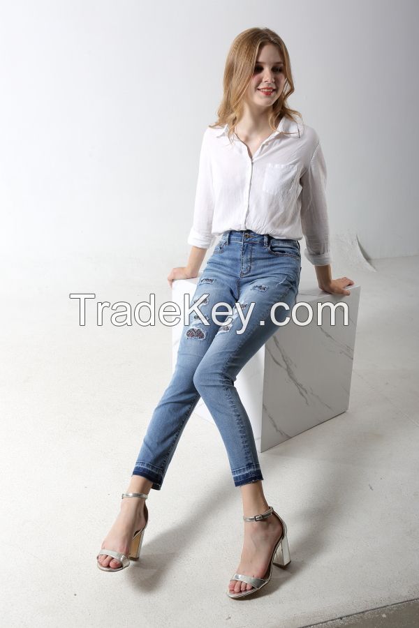 Woman's slim denim jeans with distress and patches with rhinestones