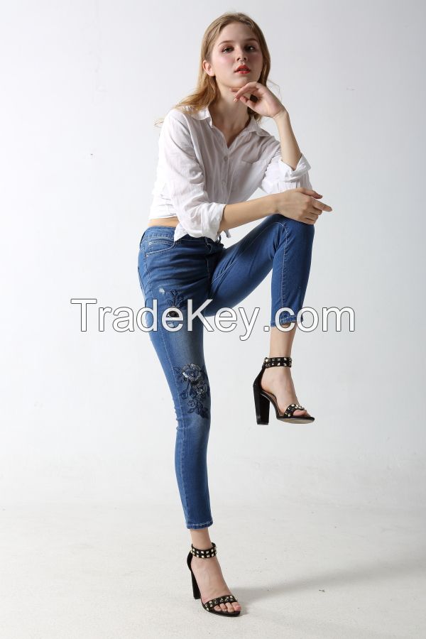 Woman's slim denim jeans with distress and patches with rhinestones