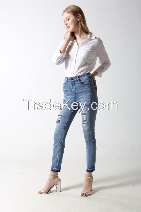 Woman's slim denim jeans with distress and patches with rhinestones