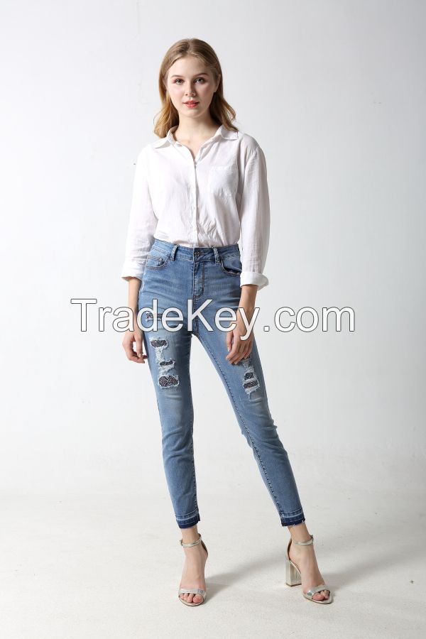 Woman's slim denim jeans with distress and patches with rhinestones