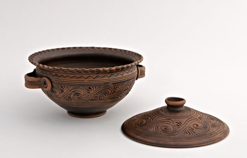 Ceramic bowl with handles and lid made of red clay.