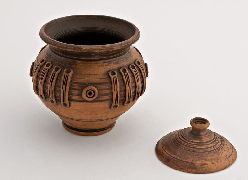 Ceramic pot with lid for cooking made of red clay.