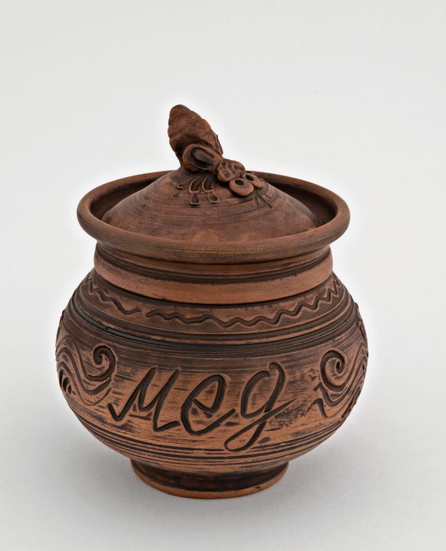 Brown ceramic pot with lid for honey made of red clay.