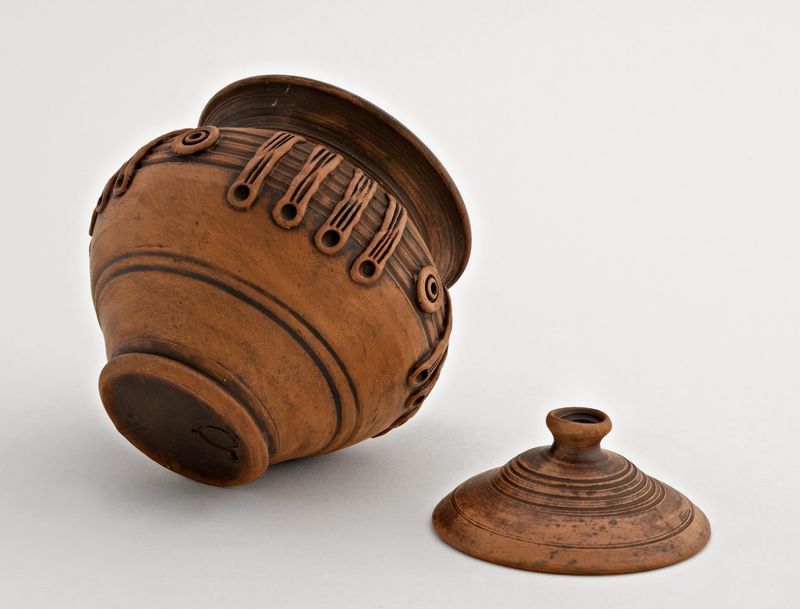 Ceramic pot with lid for cooking made of red clay.