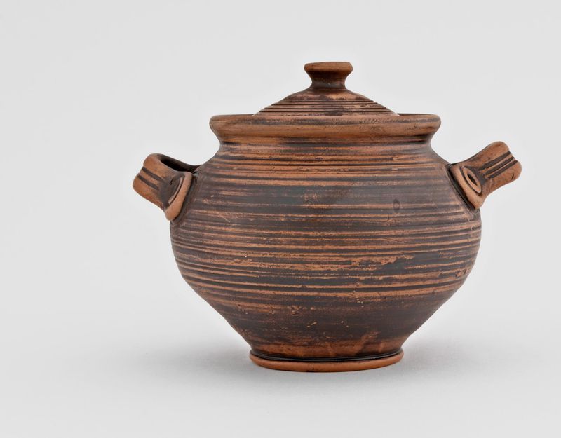 Brown big ceramic pot with lid made of red clay. 