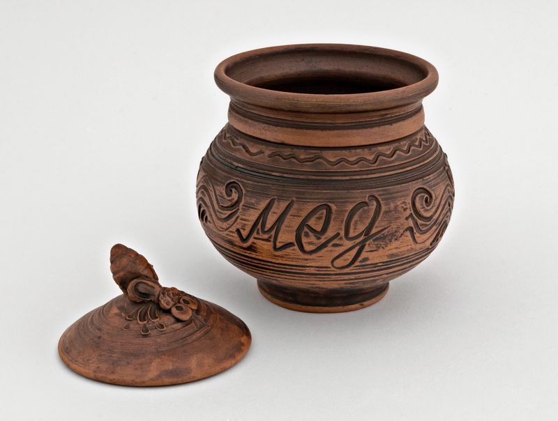 Brown ceramic pot with lid for honey made of red clay.