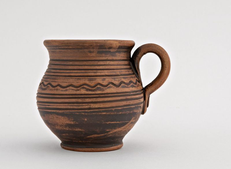 Handmade decorative coffee mug made of red clay.