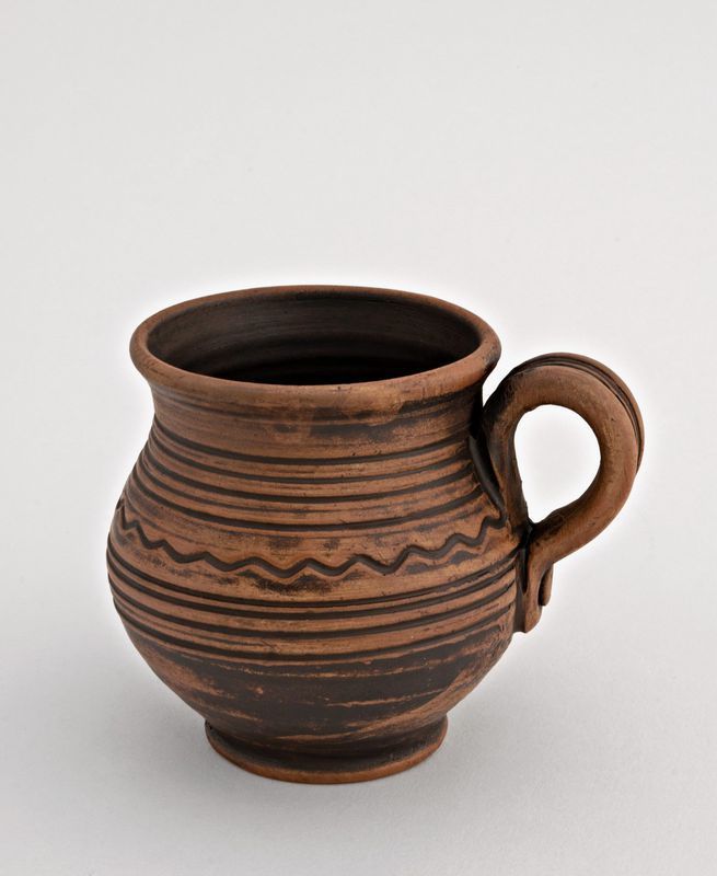 Handmade decorative coffee mug made of red clay.
