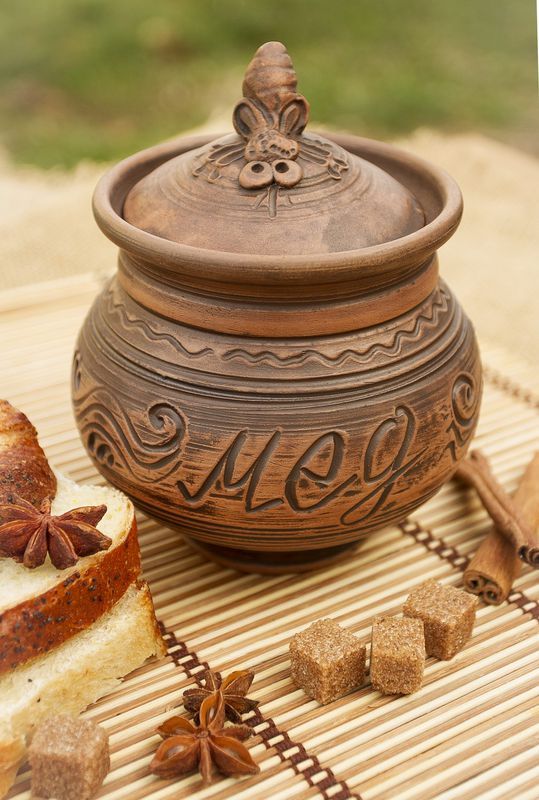 Brown ceramic pot with lid for honey made of red clay.