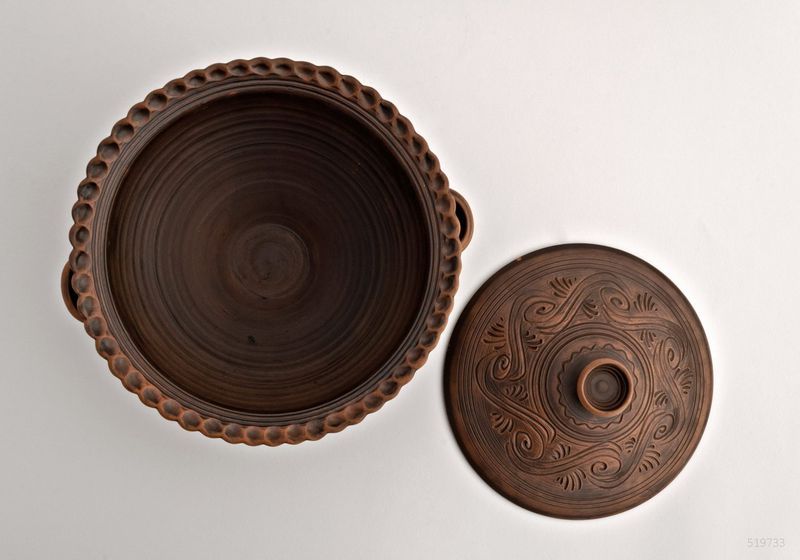 Ceramic bowl with handles and lid made of red clay.