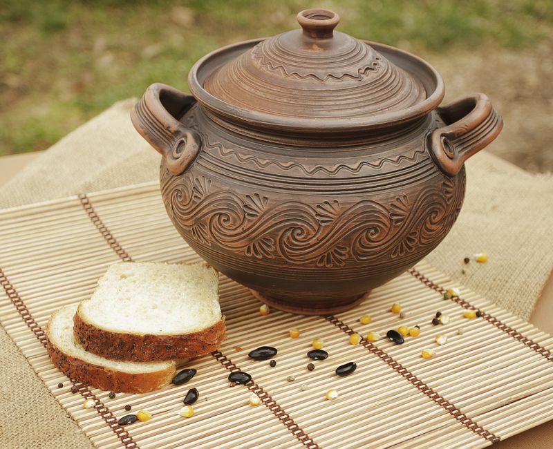 Big brown ceramic pot with lid made of red clay.