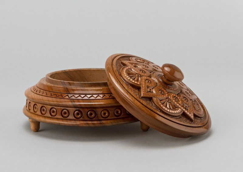 Round wooden jewelry box with knob handle and hand carved pattern.