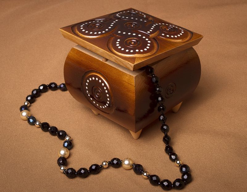 Varnished carved jewelry box inlaid by beads.