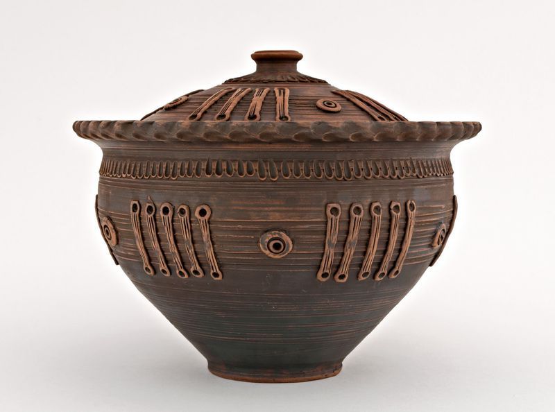 Brown ceramic pot with lid made of red clay.