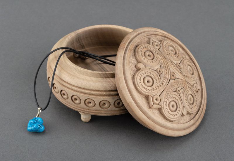 Round wooden jewelry box with hand carved pattern.