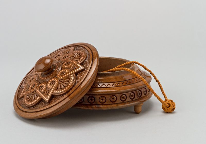 Round wooden jewelry box with knob handle and hand carved pattern.