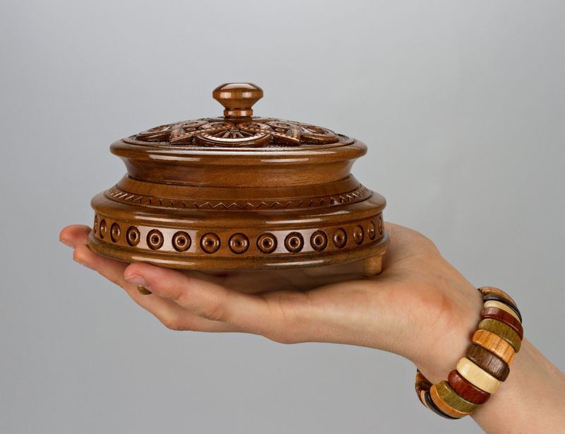 Round wooden jewelry box with knob handle and hand carved pattern.