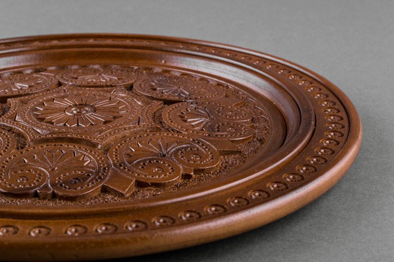 Wooden brown plate with hand carved pattern.
