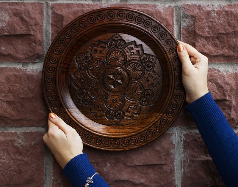 Handmade wall wooden plate with carved pattern.