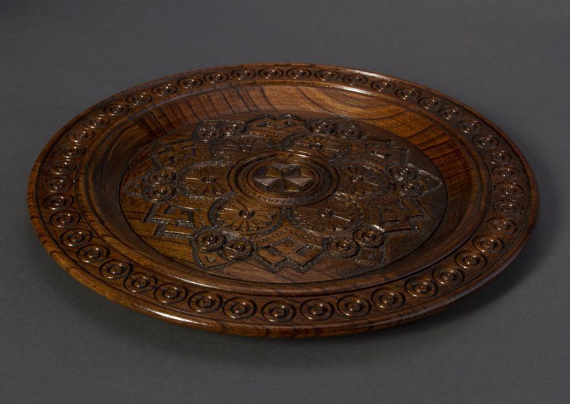 Handmade wall wooden plate with carved pattern.